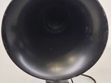 an old black speaker on a stand with a cord