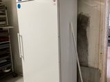 a white refrigerator in a room with a broom on the floor