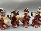 three figurines of people with musical instruments on a gray surface