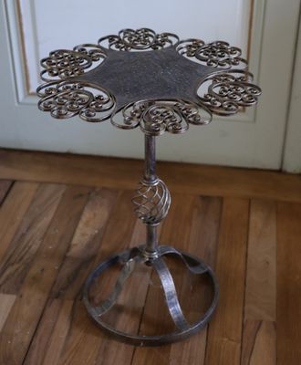 une petite table en métal ornée d'un motif floral