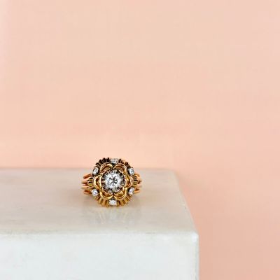 a close up of a gold and diamond ring on a marble block