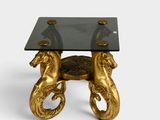 an image of a table with a glass top and two golden horses on it