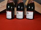three bottles of wine sitting next to a wooden box on a table