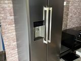 a large stainless steel refrigerator in a kitchen with a brick wall behind it