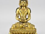 a gold statue of a buddha sitting on a lotus base