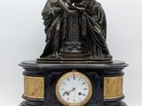 une statue représentant deux femmes assises sur une table, avec une horloge devant elles