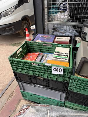 a pile of books in a green crate on the sidewalk