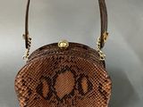 an image of a brown snake skin purse on a gray background