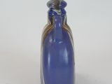 a blue glass bottle with a silver lid on a white surface