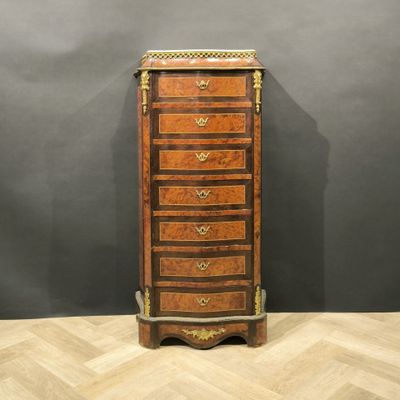a tall wooden chest of drawers with a marble top