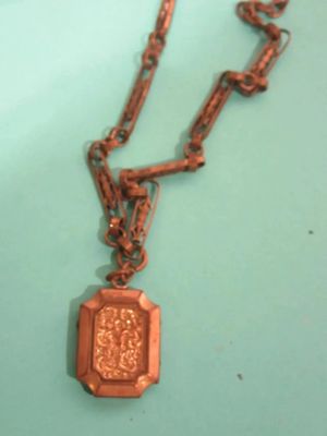 un collier ancien avec un médaillon suspendu à une chaîne, posé sur une table