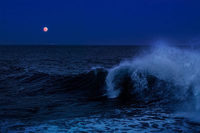 les vagues qui déferlent dans l'océan la nuit, sous une pleine lune