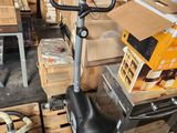 an image of a stationary exercise bike in a warehouse with boxes on the floor