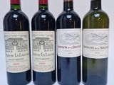 quatre bouteilles de vin sont alignées sur une surface blanche