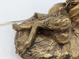 a bronze statue of a woman sitting on a rock