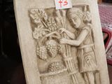 une statue représentant une femme tenant un panier de raisins posé sur une table