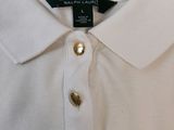 the shirt is white with gold buttons on the collar