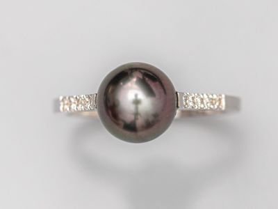 gros plan d'une bague en perles et diamants sur une surface blanche
