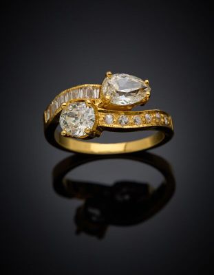 a close up of a gold ring with two diamonds on a black surface