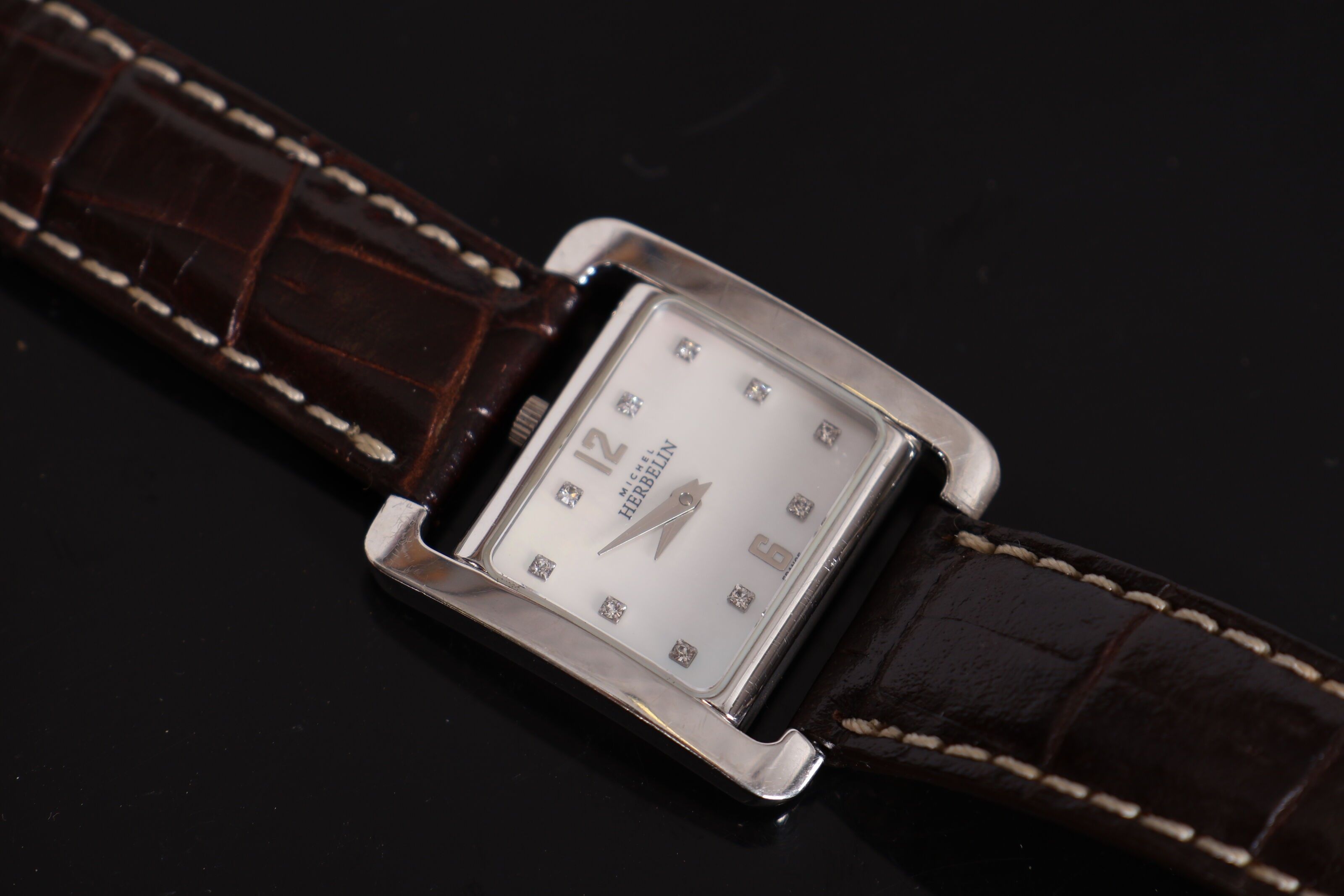 MICHEL HERBELIN. Montre bracelet de dame type H en acier, fond nacré, index à chiffres romains et strass. Bracelet en...