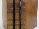 two old books sitting on top of each other on a white surface