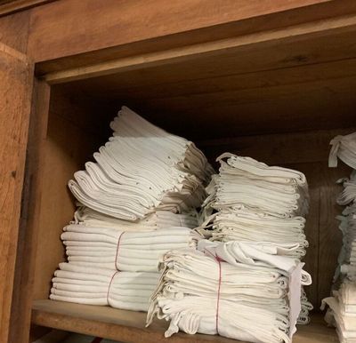 plusieurs piles de serviettes blanches pliées, posées sur une étagère en bois dans un placard