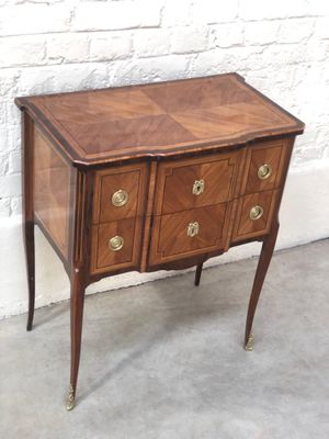 a small wooden chest of drawers on a table