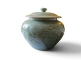 a green vase with a lid on a white surface
