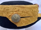 an image of a black hat with gold trim and a silver button