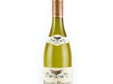 the bottle of white wine is sitting on a white surface