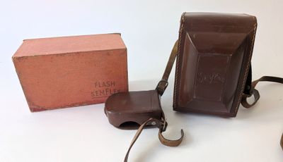 une mallette marron et un sac marron posés sur une table blanche
