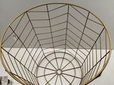 gold metal wire basket on a white table with a pair of scissors