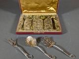 silverware in a red case with gold lining and a spoon, fork, and spoon rest