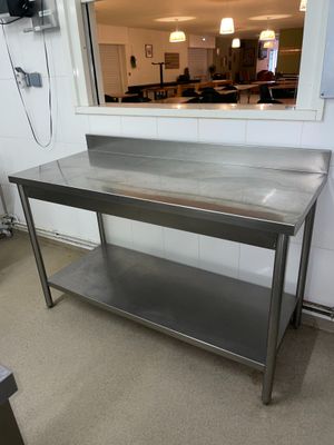 une table en acier inoxydable avec un miroir accroché au mur