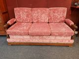 une photo d'un canapé rose posé dans une pièce, à côté d'une commode