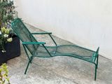 a green lawn chair that is sitting on the concrete