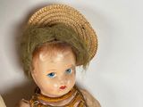 a small doll with a hat and dress on a table