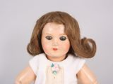 a small doll with brown hair and a white dress