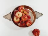 a bowl of peaches sitting on a white table