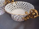 two white bowls with gold handles sitting on a table