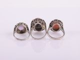 three silver rings with different colored stones on a white surface