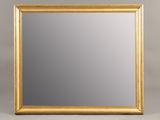 a gold framed mirror on a grey background