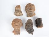 four pieces of clay with a face and a head on a white surface