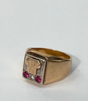 gros plan d'une bague en or avec une pierre rouge au centre