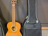 trois guitares sont alignées contre un mur, à côté d'un étui à guitare