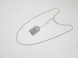 a silver tag on a gold chain on a white surface