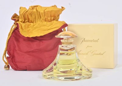 un petit flacon de parfum posé à côté d'un sac rouge