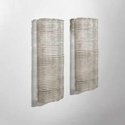 une paire de vases en verre blanc posés sur un mur blanc, sur fond blanc