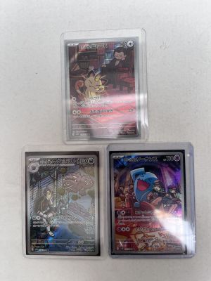 three different pokemon cards in plastic cases on a white surface
