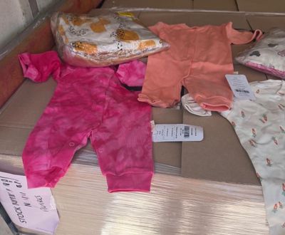 une pile de vêtements de bébé posée sur une boîte en carton
